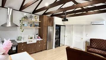 A modern kitchen with wooden beams, stainless steel appliances, and a brown leather sofa.
