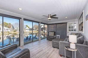 A spacious living area with a view of a dock and water, a ceiling fan, and a cozy seating arrangement. - Ocean Pines Oasis | Firepit, 4BR & 10 Min to Beach (Ocean Pines)