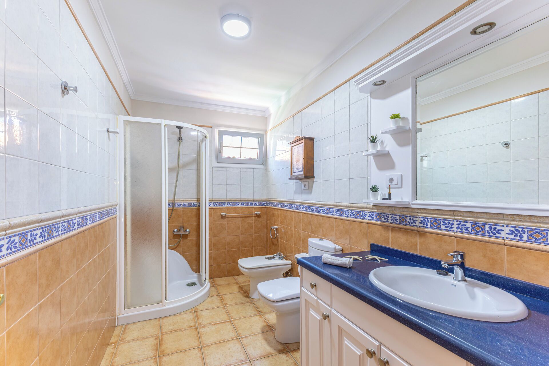 Een badkamer met douche, toilet, wastafel en een grote spiegel.