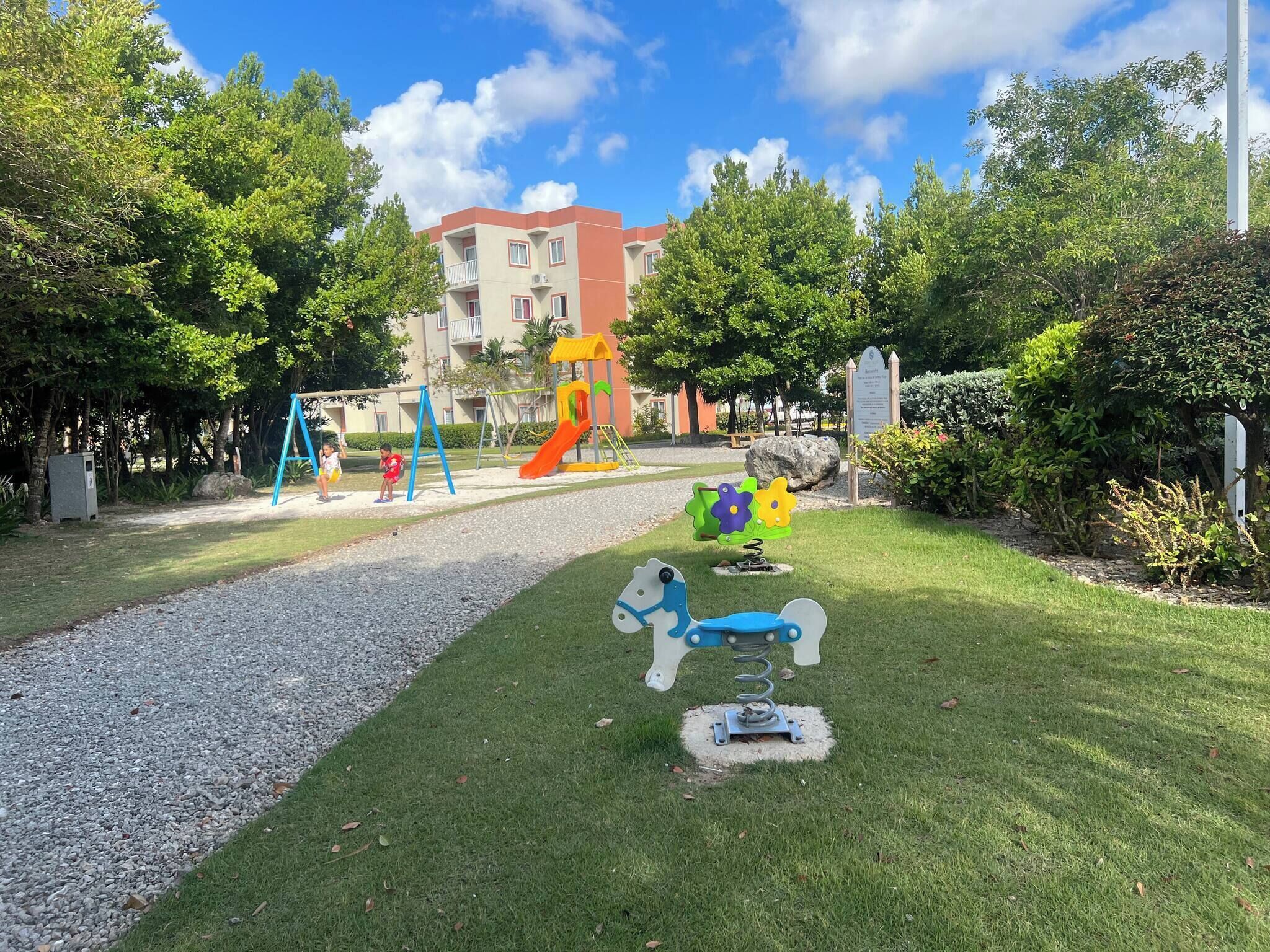 Une aire de jeux avec des balançoires, un toboggan et une structure d’escalade.