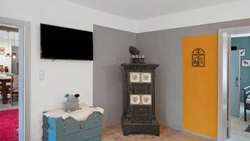A room with a television, a blue chest of drawers, a decorative cabinet, and a door with a unique design.