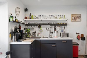 A kitchen with a sink, cabinets, and various kitchen utensils.