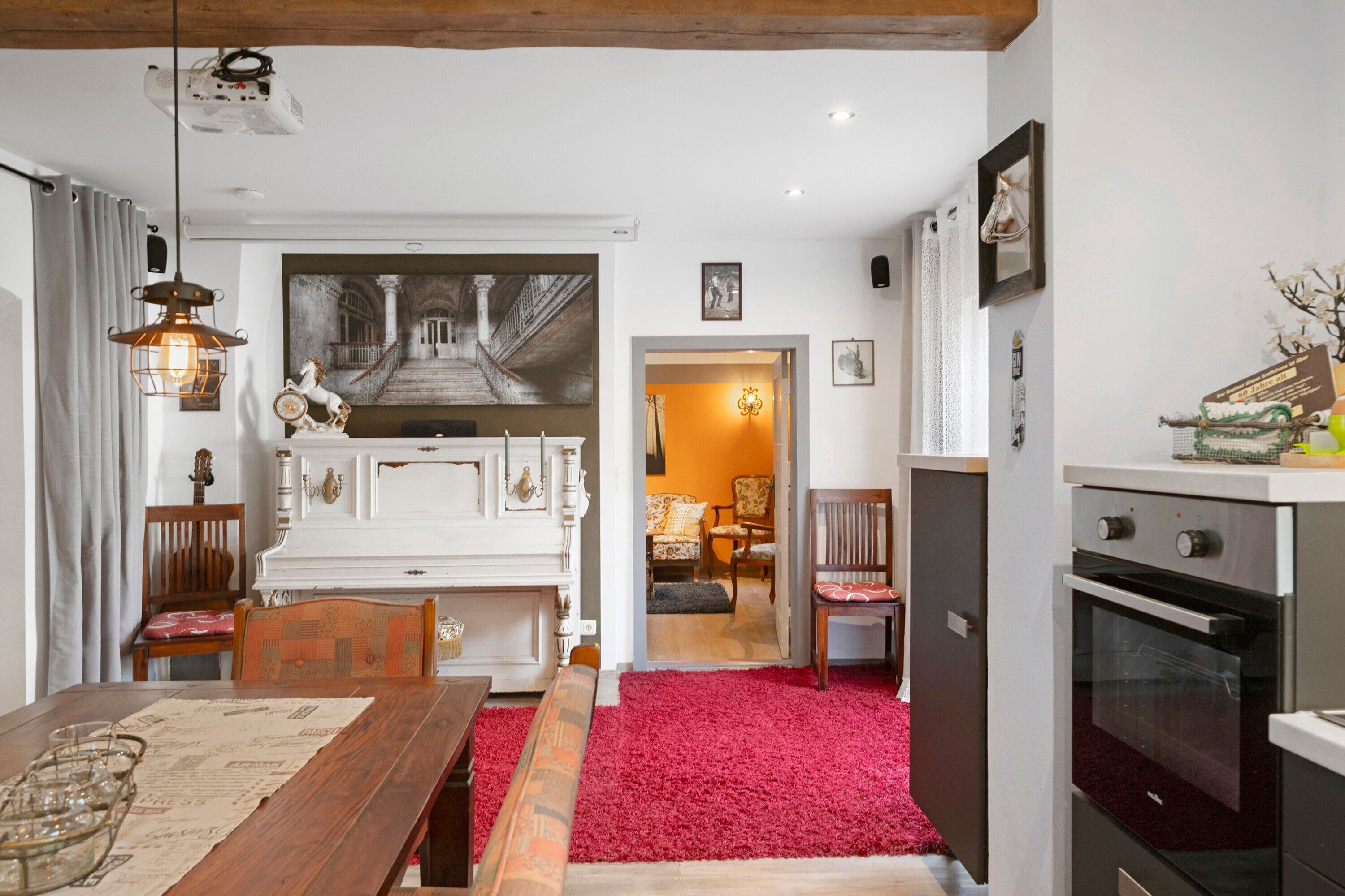 A dining area with a wooden table, chairs, and a red carpet.