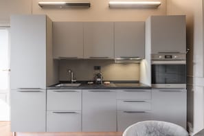 A modern kitchen with built-in appliances, a countertop, and a chair. - PALERMO, 18 - Brera from above: two-room apartment with terrace (Milan)