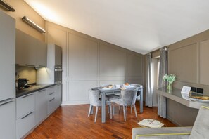 A modern kitchen with grey cabinets, a dining table with chairs, and a small seating area with a sofa. - PALERMO, 18 - Brera from above: two-room apartment with terrace (Milan)