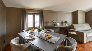 En moderne stue med et spisebord, grå polstrede stole, en grå sofa og et lille sofabord.