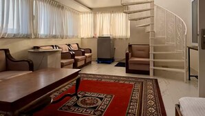 A spacious living room with a large window, a staircase, and a dining area.