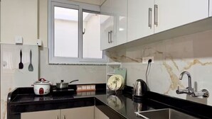 A kitchen with a black countertop, white cabinets, a window, and a sink.