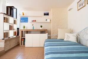Ein Schlafzimmer mit einem Bett, einem Bücherregal, einem Schreibtisch und einer Wandablage mit Dekoration.