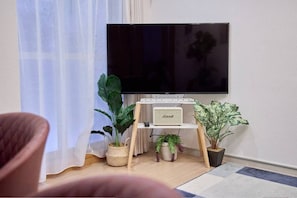 A living room with a flat-screen TV, a small speaker, and several potted plants. - 4 bedrooms and 2 bathrooms｜Condominiums can accommodate up to 10 people, making them perfect for a 3-generation family vacation. (京都市下京区下鱗形町)