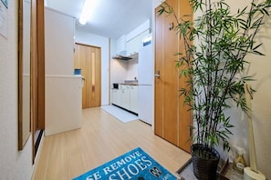 A hallway with a blue mat, wooden doors, a kitchen area, and a bamboo plant. - 4 bedrooms and 2 bathrooms｜Condominiums can accommodate up to 10 people, making them perfect for a 3-generation family vacation. (京都市下京区下鱗形町)