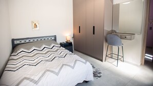 A bedroom with a bed, nightstand, wardrobe, chair, and a mirror.