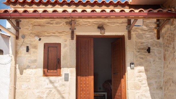 A stone building with a tiled roof, a wooden door, and a small window.