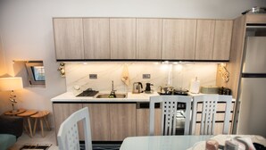 A modern kitchen with wooden cabinets, a countertop, and a dining area with chairs.