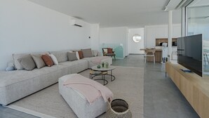 Ein modernes Wohnzimmer mit einem Ecksofa, einem Couchtisch und einem Fernseher auf einem Holzboden.