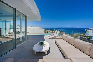 Un espai exterior modern amb piscina, gandules i un sofà.
