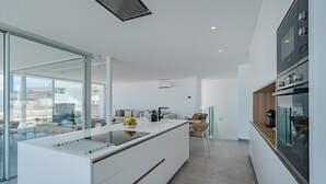 Eine moderne Küche mit einer großen Kochinsel, einem Essbereich mit einer Couch und Blick auf die Stadt.
