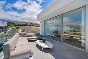 Un espace de vie extérieur moderne, comprenant un canapé, une table basse et des portes vitrées donnant sur un patio.