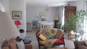 Ett vardagsrum med en soffa, ett träbord, en lampa och en matplats i bakgrunden.