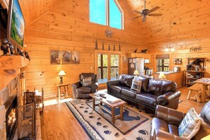 A cozy cabin interior with a fireplace, leather furniture, and a kitchen area. - Douglas Lake Cabin Retreat・Beautiful Views・Hot Tub (Sevierville)