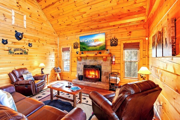 A log cabin interior with leather furniture, a stone fireplace, and a television displaying 'Casago'. - Douglas Lake Cabin Retreat・Beautiful Views・Hot Tub (Sevierville)