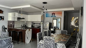 A modern kitchen with white cabinets, a central island, and a dining area with patterned chairs.