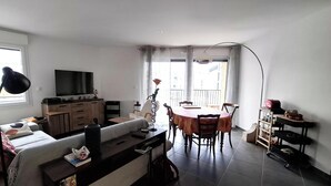 Un salon comprenant un canapé, un téléviseur, une table à manger et des chaises.