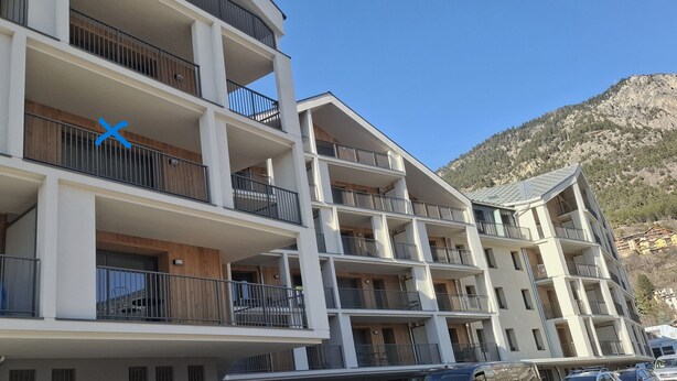 Un hôtel à plusieurs étages, doté de balcons, d’une façade en bois et situé dans un cadre montagneux.
