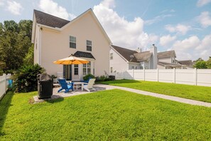 A two-story house with a patio area featuring outdoor furniture and a grill. - Dogs Welcome! Adorable 3-bedroom Coastal Home in Historic Old Town Bluffton (Bluffton)