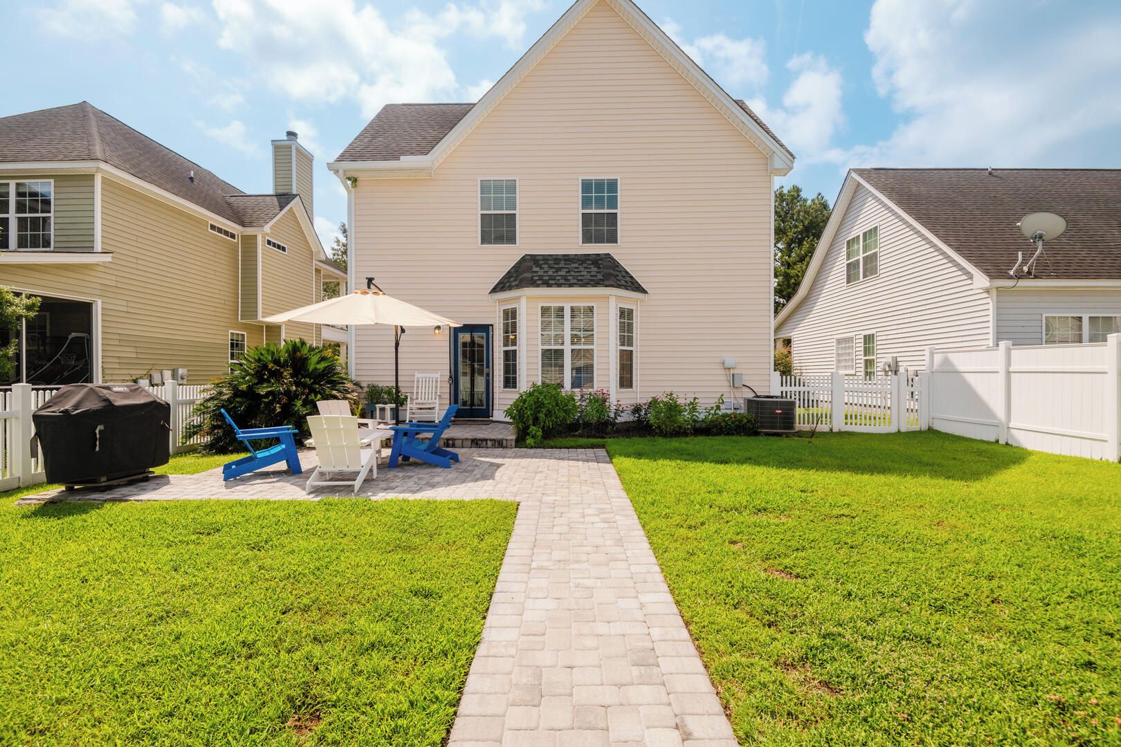 A residential property with a paved patio, outdoor seating, and a white fence.