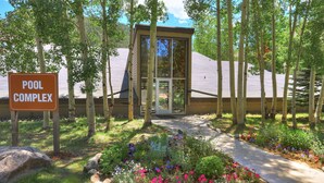 A pool complex entrance with a sign, surrounded by a garden with various plants and a pathway. - Beautiful 2BR/2BA condo in Keystone, offering a tranquil mountain retreat (Keystone)