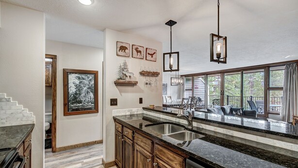 A kitchen with granite countertops, wooden cabinets, a built-in dishwasher, and a large window overlooking a deck. - Beautiful 2BR/2BA condo in Keystone, offering a tranquil mountain retreat (Keystone)