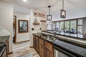 A kitchen with granite countertops, wooden cabinets, a built-in dishwasher, and a large window overlooking a deck. - Beautiful 2BR/2BA condo in Keystone, offering a tranquil mountain retreat (Keystone)