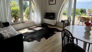A spacious living area with a large window, a black leather rug, a white sofa, and a dining table with chairs. - WHOLE APARTMENT WITH PARK AND SEA VIEW TROUVILLE SUR MER. (Trouville-sur-Mer)