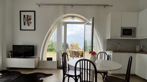 A modern kitchen with white cabinets, a microwave, and a dining area with a round table and chairs. - WHOLE APARTMENT WITH PARK AND SEA VIEW TROUVILLE SUR MER. (Trouville-sur-Mer)