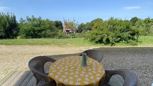 A round outdoor table with wicker chairs, a yellow tablecloth, and a pitcher on the deck. - WHOLE APARTMENT WITH PARK AND SEA VIEW TROUVILLE SUR MER. (Trouville-sur-Mer)