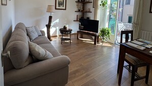Un salon avec un canapé, un téléviseur, une table basse en bois, une lampe et un ventilateur de plafond.