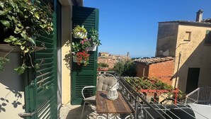 Un balcon avec une table et des chaises, des plantes en pot et une vue sur la ville.