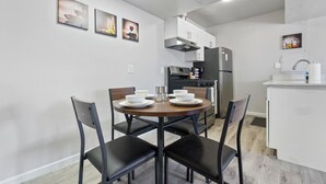 Una cucina moderna con mobili bianchi, un frigorifero nero e un tavolo da pranzo con quattro sedie.