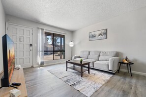 A modern living room with a sofa, coffee table, and a painting on the wall. - Charming 1-bedroom apartment with AC in Mesa - Great for Extended Stay Guests (Mesa)