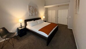 A hotel room with a bed, two bedside lamps, a chair, a painting on the wall, and a set of double doors. - Entire Upper Level Home w/Fast Wi-Fi •20 Min SEA, Parking (Kent)