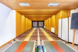 A long, narrow room with wooden walls and ceiling, a central aisle, and a chalkboard on the right.