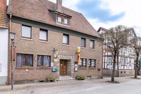 A traditional brick building with a sign reading 'GASTHAUS' and a wooden door.