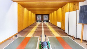 Una sala llarga i estreta amb parets de fusta i sostre inclinat, amb un passadís central i una pissarra a la dreta.