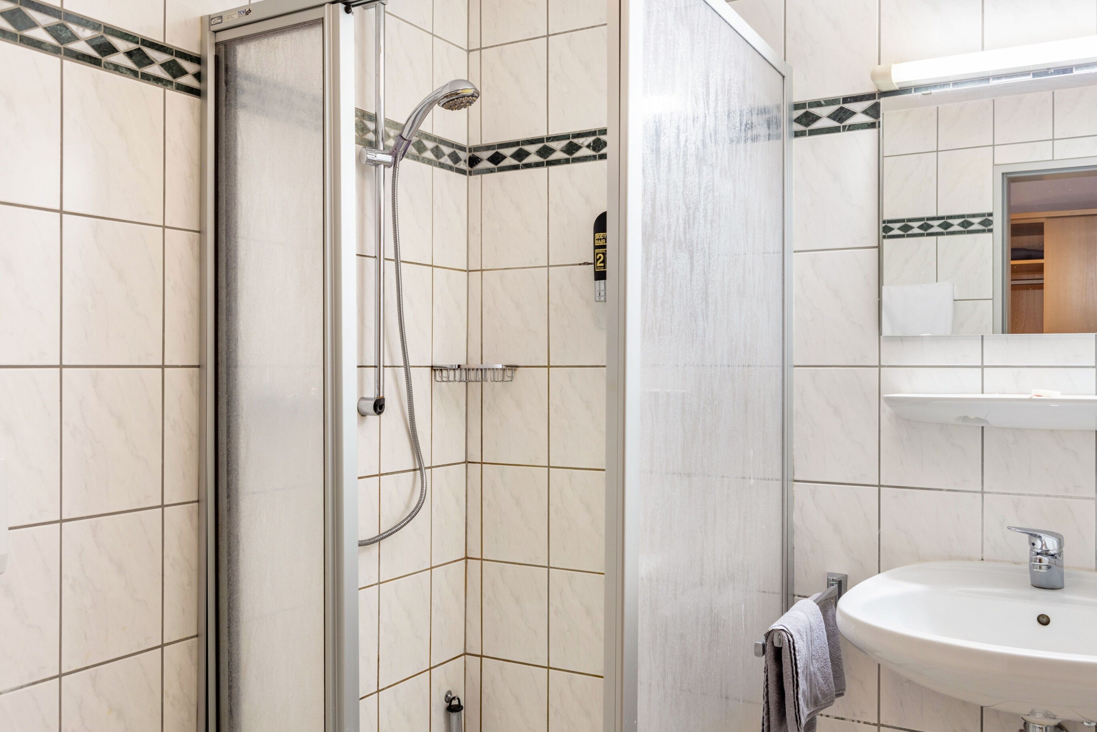 Un bagno con doccia, lavandino e specchio.
