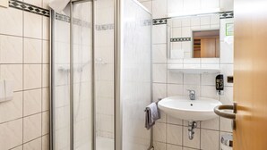 Un bany amb plat de dutxa de vidre, un lavabo i un mirall.