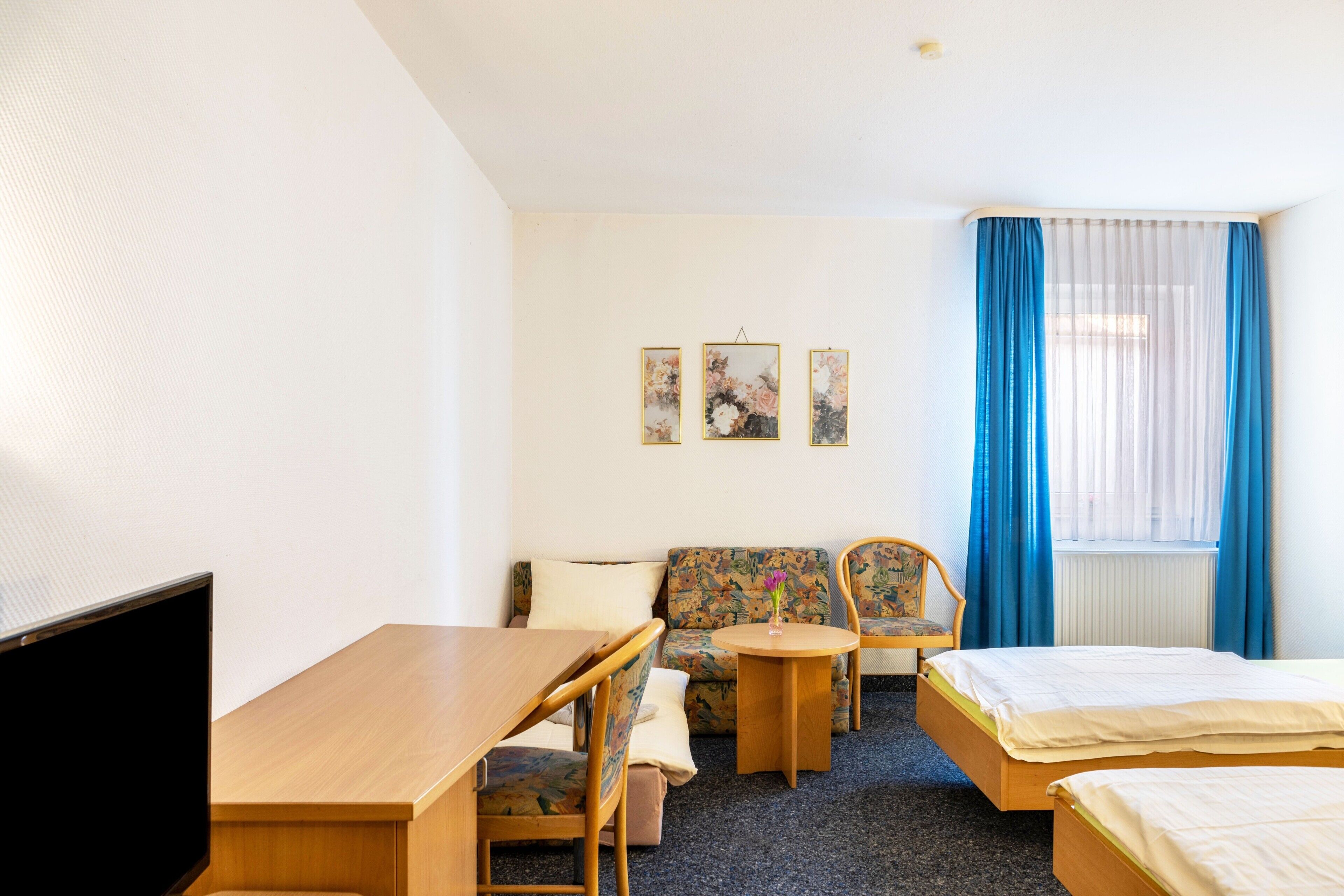 Une chambre d’hôtel équipée d’un lit, d’un bureau, d’une chaise, d’un canapé et d’une télévision.