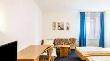 Une chambre d’hôtel équipée d’un lit, d’un bureau, d’une chaise, d’un canapé et d’une télévision.
