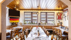 Un restaurante con una larga mesa de madera, sillas y una bandera alemana.