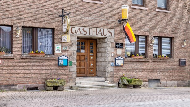 Un edificio de ladrillo con un letrero que dice 'GASTHAUS' sobre la entrada.